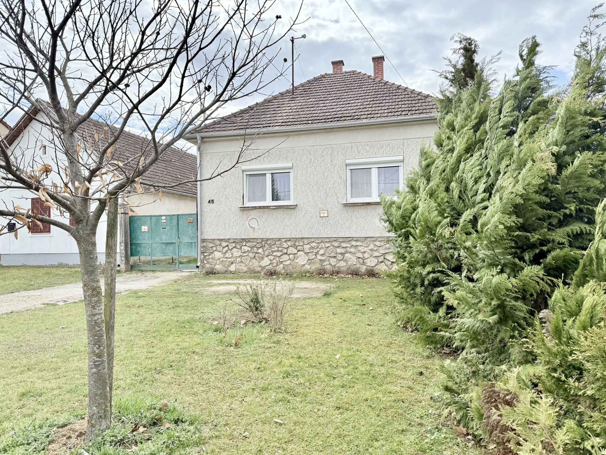 A ház az utca felől, kőlábazattal és cseréptetővel
